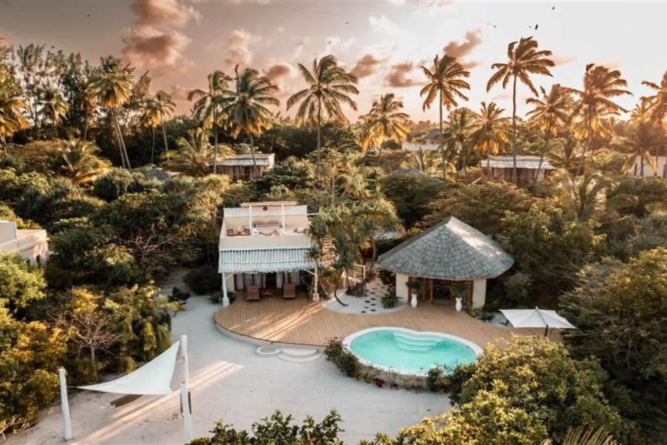 A resort with a pool, a gazebo, and a house surrounded by palm trees.