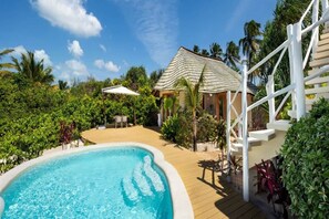 A pool area with a wooden deck, a covered seating area, and lush greenery. - Indian Ocean Beachfront Sanctuary (Paje)