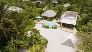 A resort with a central pool, surrounded by lush greenery and palm trees. - Family Pool Suite Deluxe (Paje)
