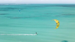 A person parasailing over turquoise water with a yellow sail. - Family Pool Suite Deluxe (Paje)