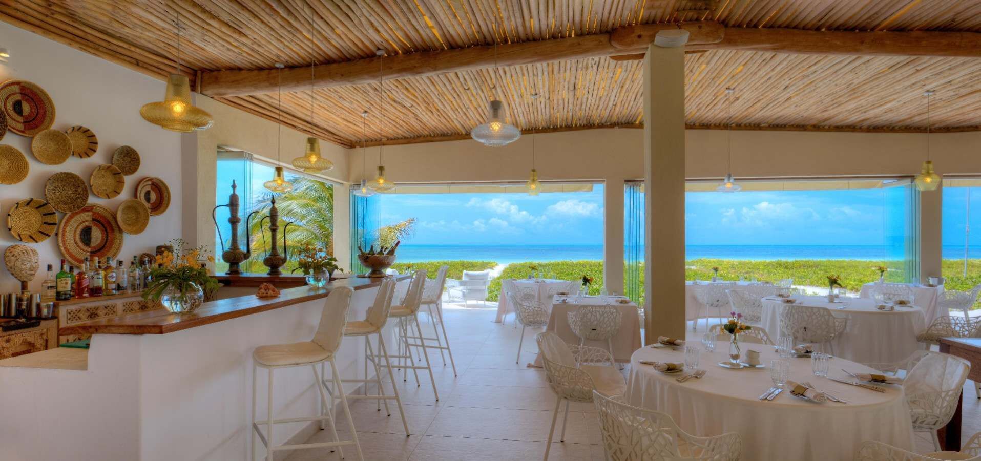En restaurang med utsikt över havet, med en bardel som har barstolar och bord för servering.
