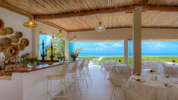 Ein Restaurant mit Meerblick, das eine Bar mit Hockern und Tischen zum Essen bietet.