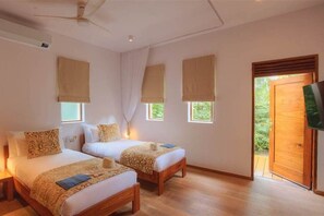 Ein Zimmer mit zwei Betten, einem Deckenventilator und einem an der Wand befestigten Fernseher.