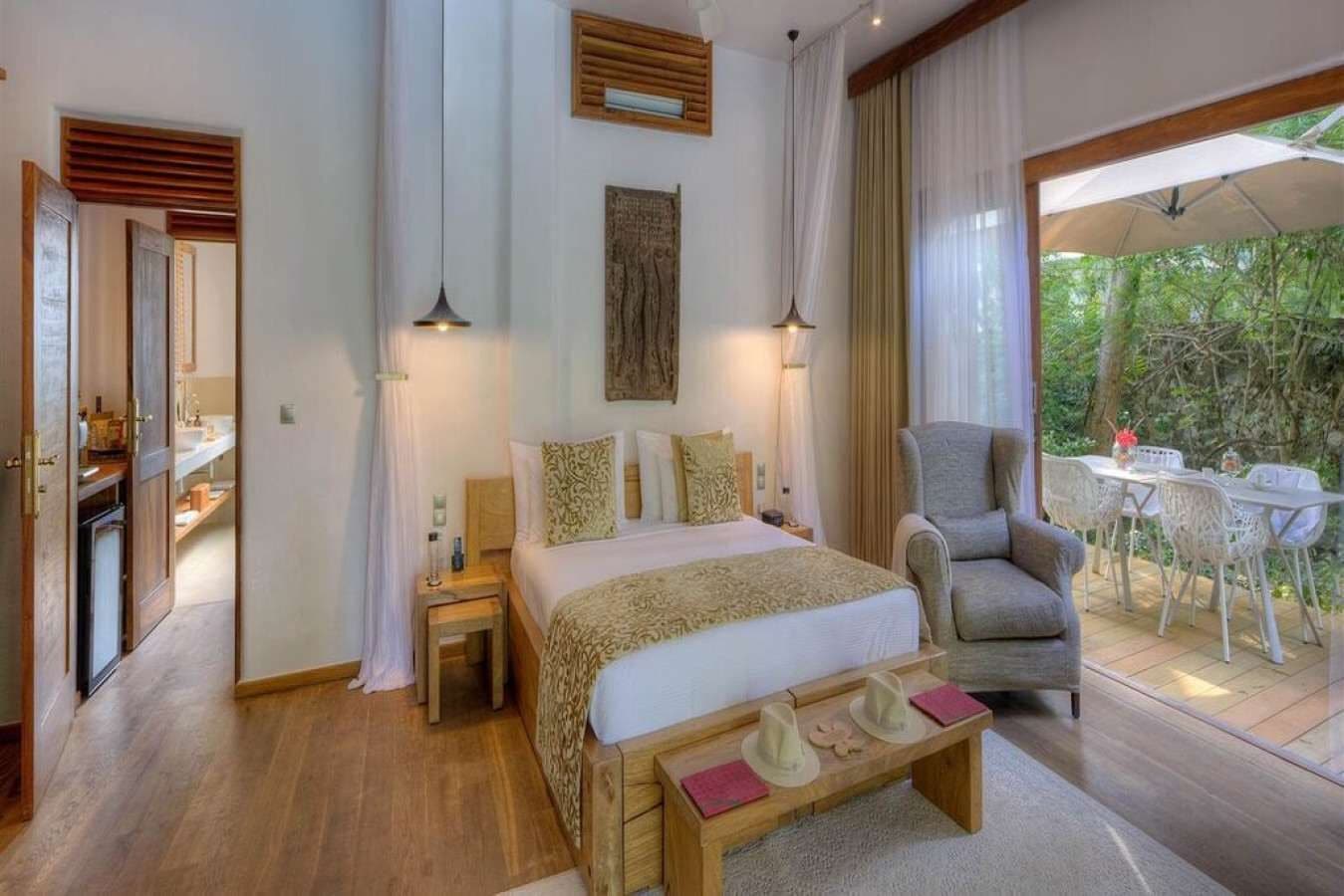 A bedroom with a bed, bedside tables, a chair, and a view of the outdoors.