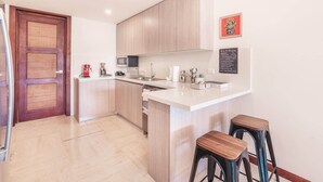 A modern kitchen with wooden cabinets, a white countertop, and two stools. - Comfortable apt with 2br w balcony in Portillo (Las Terrenas)