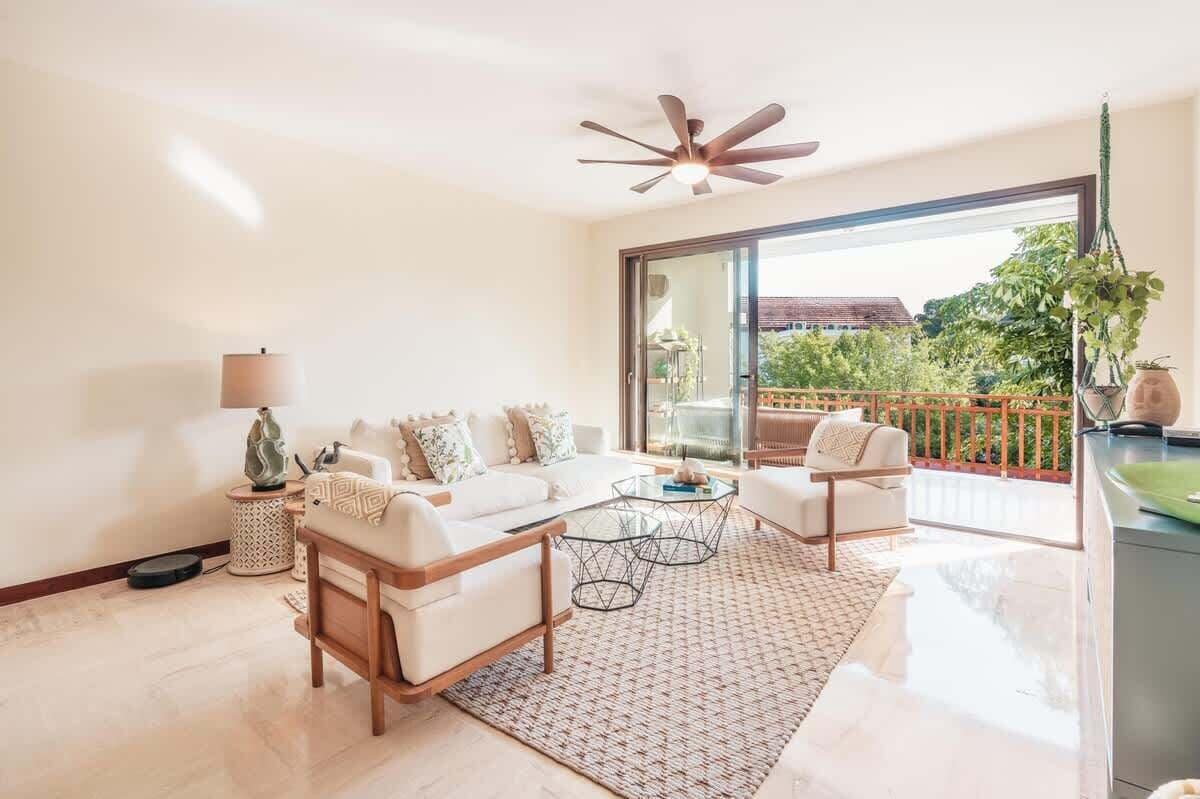 A modern living room with a sofa, armchairs, a coffee table, and a ceiling fan.
