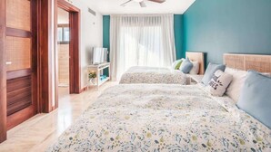 A bedroom with two beds, a ceiling fan, a TV, and a window with curtains. - Comfortable apt with 2br w balcony in Portillo (Las Terrenas)