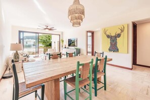 Ein Essbereich mit einem Holztisch und grünen Stühlen, einer Kandelaber und einem großen Gemälde eines Rehs an der Wand.