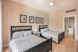 A bedroom with two beds, a nightstand, and framed botanical prints on the wall. - Villa with ocean view bbq pool resort access (Sánchez)