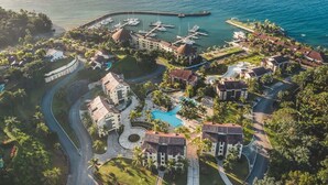 An aerial view of a resort with multiple buildings, a central swimming pool, and a marina with boats. - Villa with ocean view bbq pool resort access (Sánchez)