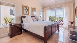A bedroom with a large bed, a nightstand, a dresser, and a view of the outdoors. - Villa with ocean view bbq pool resort access (Sánchez)