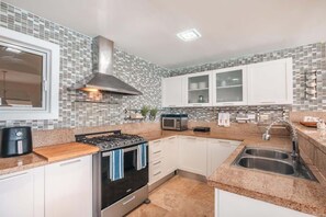 Eine moderne Küche mit weißen Schränken, einer Edelstahl-Dunstabzugshaube, einer Mikrowelle und einer Spüle mit zwei Becken.