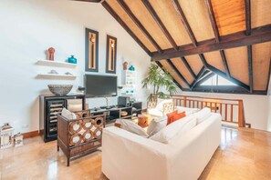 A spacious living room with a high ceiling, a white sofa, a wooden coffee table, and a television. - Penthouse w jacuzzi and ocean view Puerto Bahia (Sánchez)