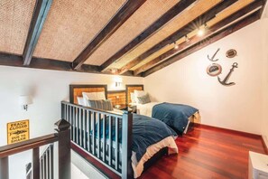 Ein Schlafzimmer mit Holzboden, einem Bett mit blauer Bettwäsche, einem Nachttisch und einer Wandlampe.