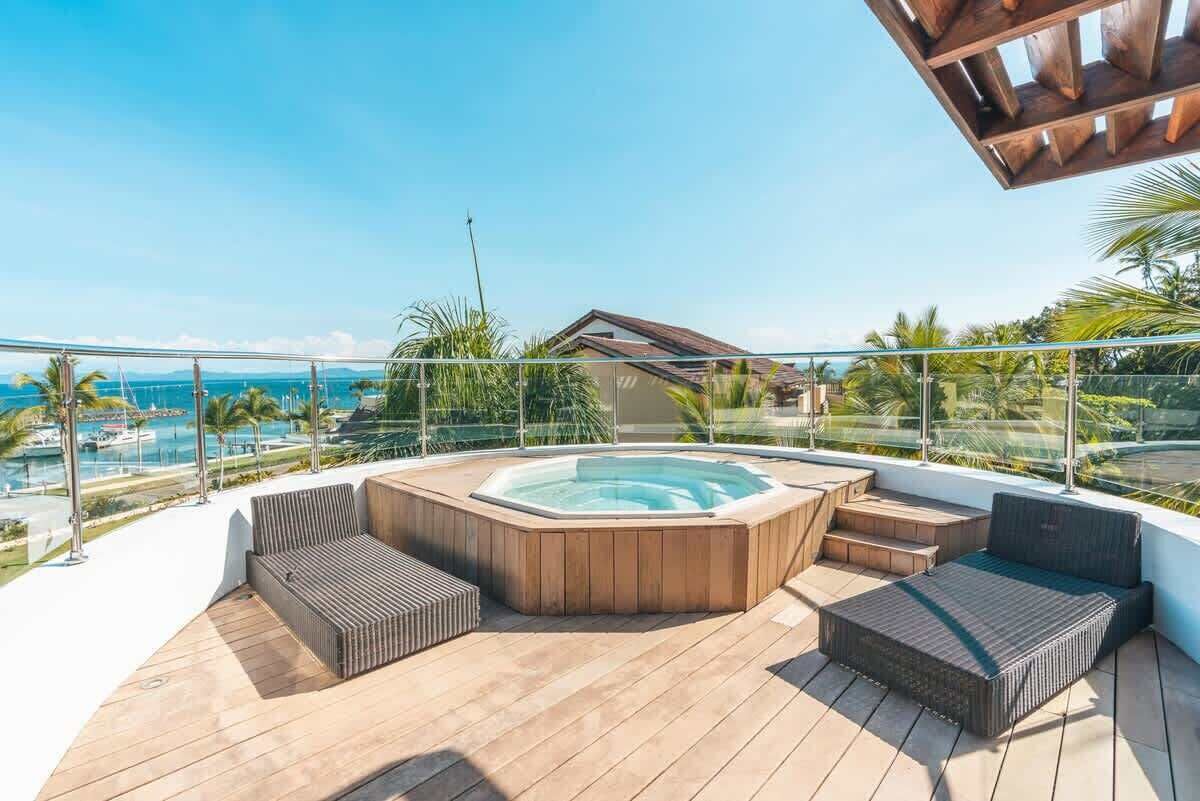 Eine Dachterrasse mit Whirlpool, Sitzbereichen und Blick auf das Meer und den Yachthafen.