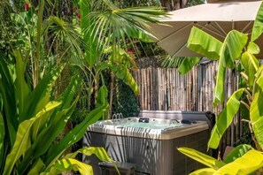 A hot tub surrounded by lush tropical plants and a bamboo fence. - Spice Route Family Room (Paje)