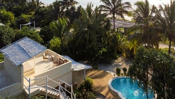 Un resort con piscina, asientos al aire libre y vistas al océano.