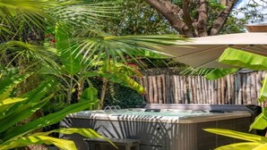 Tinaco en un jardín con valla de bambú, rodeado de plantas tropicales.