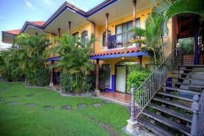 A two-story house with a balcony, a staircase, and a well-maintained garden.
