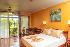 A hotel room with a bed, a sofa, a desk, and a view of the outdoors. - Rainforest Angel Suite (Bahía Ballena)