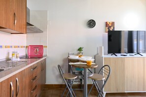 A compact kitchen with a dining area, a clock, and a flat-screen TV. - Charming Apartment | Near the Airport | Balcony | Cozy (Cruce de Arinaga)