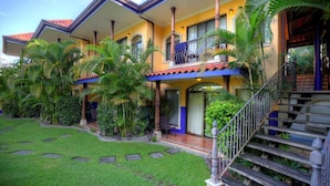 A two-story house with a balcony, a staircase, and a well-maintained garden. - Rainforest Family Angel Suite (Bahía Ballena)