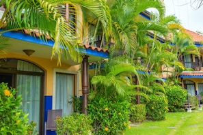 A hotel with multiple balconies, lush greenery, and a well-maintained garden.