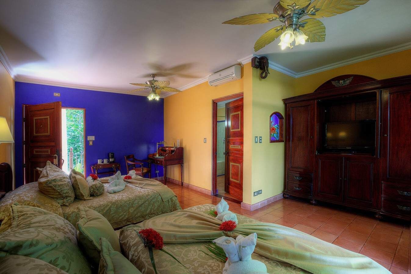 Habitación de hotel con dos camas, un escritorio, un televisor y la puerta del baño.