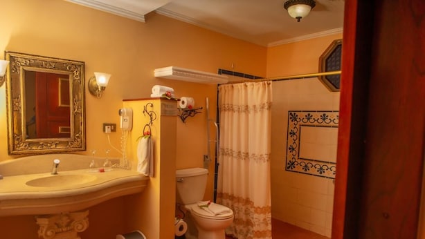 A bathroom with a pedestal sink, toilet, and shower curtain. - Rainforest Family Angel Suite (Bahía Ballena)