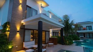 Ein modernes, zweistöckiges Haus mit Pool, Sitzgelegenheiten im Freien und einer gut beleuchteten Terrasse.