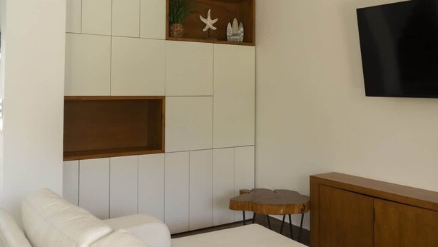 Ein modernes Schlafzimmer mit einer weißen Couch, einem Holzschrank, einem Fernseher und einem Deckenventilator.