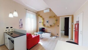 Una sala de estar moderna con sofá, mesa de comedor, televisor y área de cocina con estufa.
