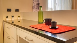 Una encimera de cocina con un tapete rojo, una botella verde y una taza negra.
