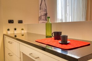 A kitchen counter with a red mat, a green bottle, and a black mug. - Loft Galileo · Design in the Heart of Monza (Monza)