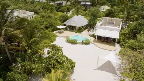 Ein Resort mit zentralem Pool, umgeben von üppiger Vegetation und Palmen.
