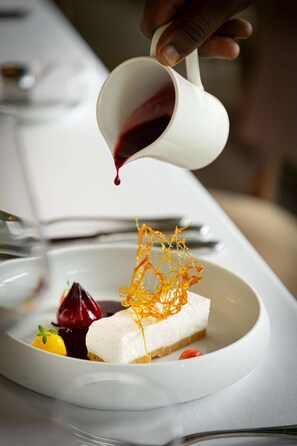 Ein Dessert mit weißem Teller, roter Soße und einer Dekoration.
