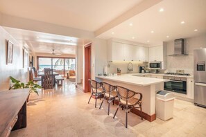 A modern kitchen with white cabinets, a central island with bar stools, and a view to the outside. - 3br 10 guests ocean view  Bbq in Samana (Sánchez)