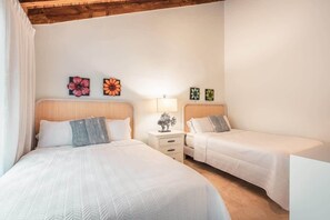Ein Hotelzimmer mit zwei Betten, einem Nachttisch mit Lampe und Wandbildern.