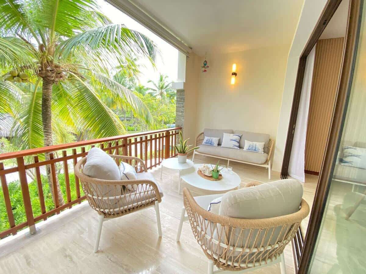 A balcony with wicker furniture, a round table, and a sofa.