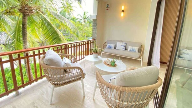 A balcony with wicker furniture, a round table, and a sofa. - Charming two-bedroom apartment in Portillo (Las Terrenas)
