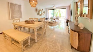 A spacious dining area with a large table, benches, and a chandelier. - Charming two-bedroom apartment in Portillo (Las Terrenas)