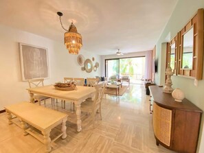 A spacious dining area with a large table, benches, and a chandelier. - Charming two-bedroom apartment in Portillo (Las Terrenas)