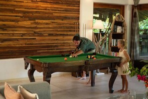 A pool table in a room with a wooden wall and a bookshelf. - Spice Route Double Room (Paje)