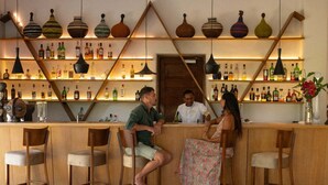 A bar area with wooden chairs, a counter, and shelves of bottles. - Spice Route Double Room (Paje)