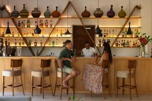 Eine Bar mit Holzhockern, einer Theke und Regalen voller Flaschen.