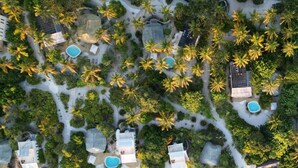An aerial view of a resort with multiple swimming pools, palm trees, and a variety of buildings. - Spice Route Double Room (Paje)