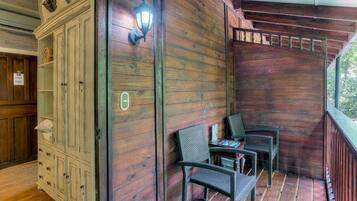A wooden cabin with a porch, a cabinet with drawers, and two wicker chairs.
