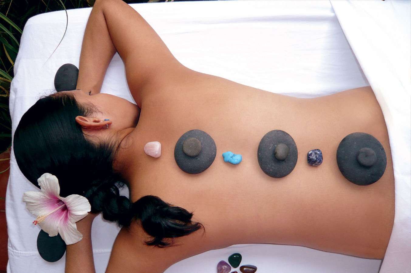 A person receiving a stone massage with various stones placed on their back.