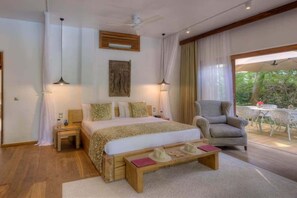 Ein Schlafzimmer mit einem Bett, Nachttischen, einem Sessel und Blick ins Freie.
