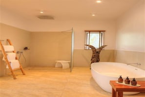 A modern bathroom with a walk-in shower, a freestanding bathtub, and a wooden ladder. - The Spice Island Grand Estate (Paje)